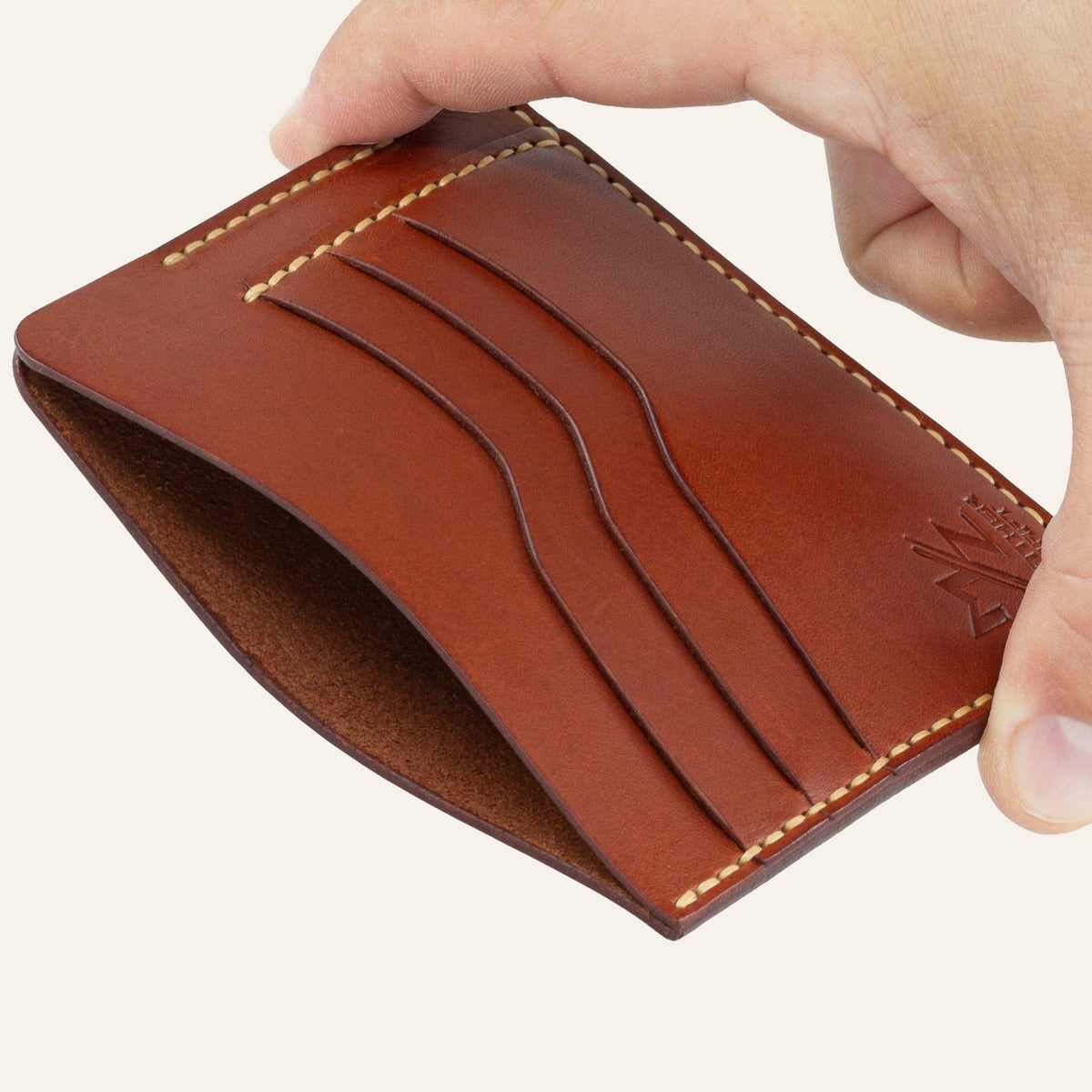 MZ Leather Craft kiremit Buttero deri ters cüzdan, el ile tutulan hafif açılı boş görünüm, ana bölmeyi ve sarı saraç dikişi detaylarını gösteren açı