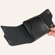 MZ Leather Craft açık dil kapaklı kompakt siyah Buttero deri cüzdan, el ile tutulan boş iç görünüm, tekli geniş kart bölmesi ve sarı el dikişi detayları