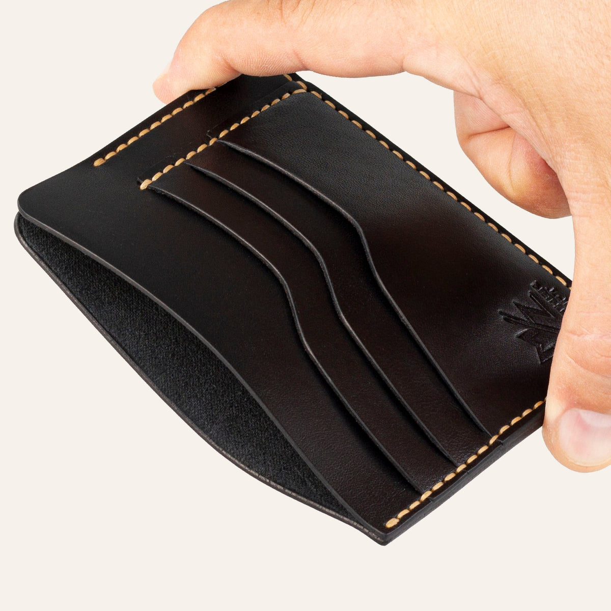 MZ Leather Craft siyah Buttero deri ters cüzdan, el ile tutulan hafif açılı boş görünüm, ana bölmeyi ve sarı saraç dikişi detaylarını gösteren açı