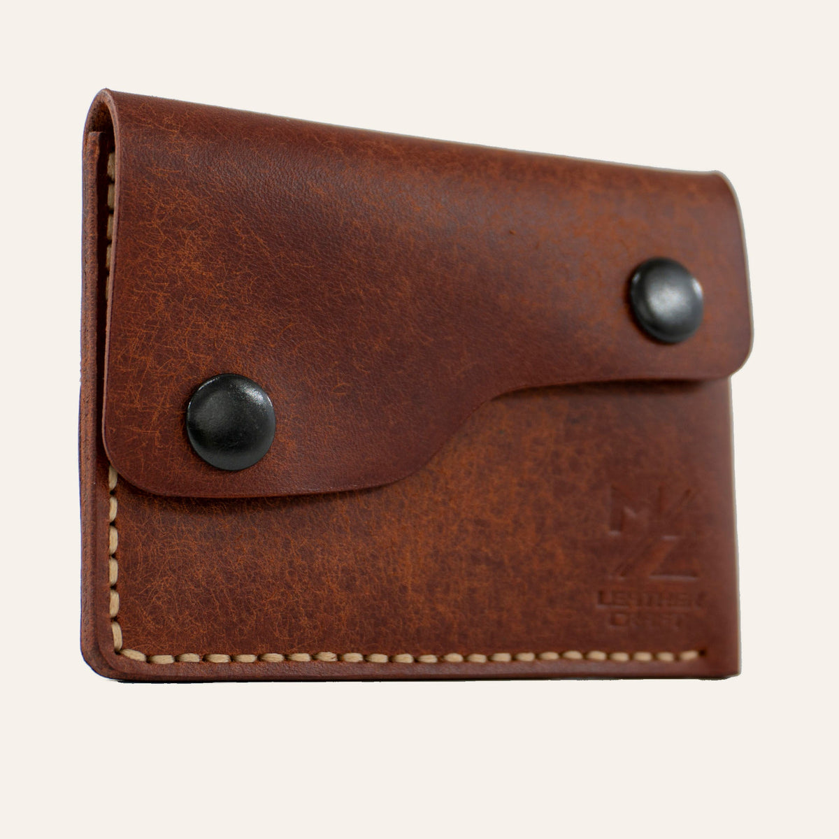MZ Leather Craft kiremit Pueblo deri kapaklı minimalist cüzdan, kapalı hafif açılı sol profil görünümü, açık gri el dikişi hattı ve mat deri dokusu