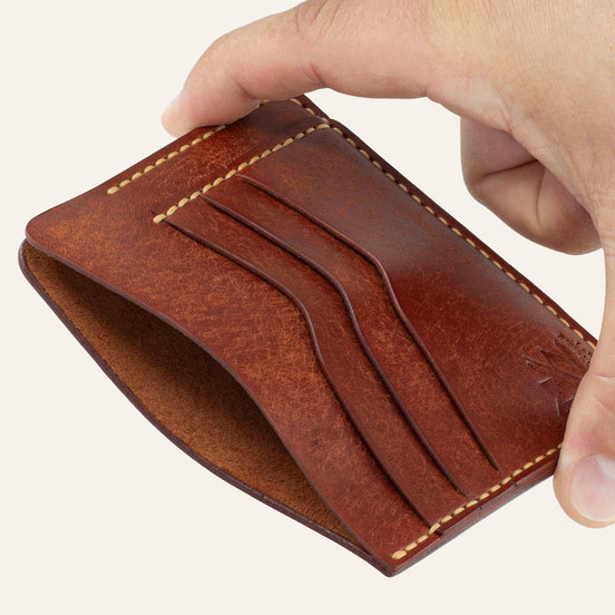MZ Leather Craft kiremit Pueblo deri ters cüzdan, el ile tutulan hafif açılı boş görünüm, ana bölmeyi ve sarı saraç dikişi detaylarını gösteren açı