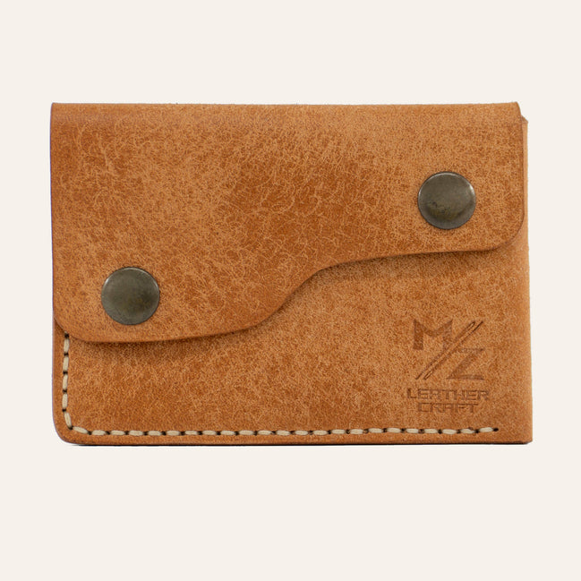 MZ Leather Craft çift çıtçıtlı kapaklı minimalist naturel Pueblo deri cüzdan, kapalı önden görünüm, asimetrik kapak formu, açık gri el dikişi ve kabartmalı MZ logosu