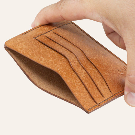 MZ Leather Craft natürel Pueblo deri ters cüzdan, el ile tutulan hafif açılı boş görünüm, ana bölmeyi ve kahverengi saraç dikişi detaylarını gösteren açı