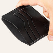 MZ Leather Craft siyah Pueblo deri ters cüzdan, el ile tutulan hafif açılı boş görünüm, ana bölmeyi ve gri saraç dikişi detaylarını gösteren açı