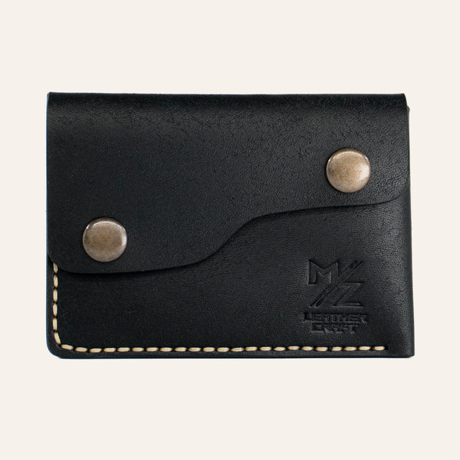 MZ Leather Craft çift çıtçıtlı kapaklı minimalist siyah Pueblo deri cüzdan, kapalı önden görünüm, asimetrik kapak formu, sarı el dikişi ve kabartmalı MZ logosu